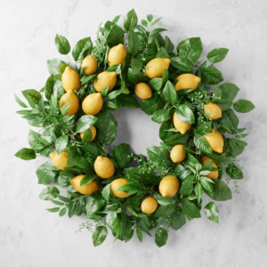 A decorative spring wreath made of green leaves and yellow lemons, arranged in a circular shape on a light background.