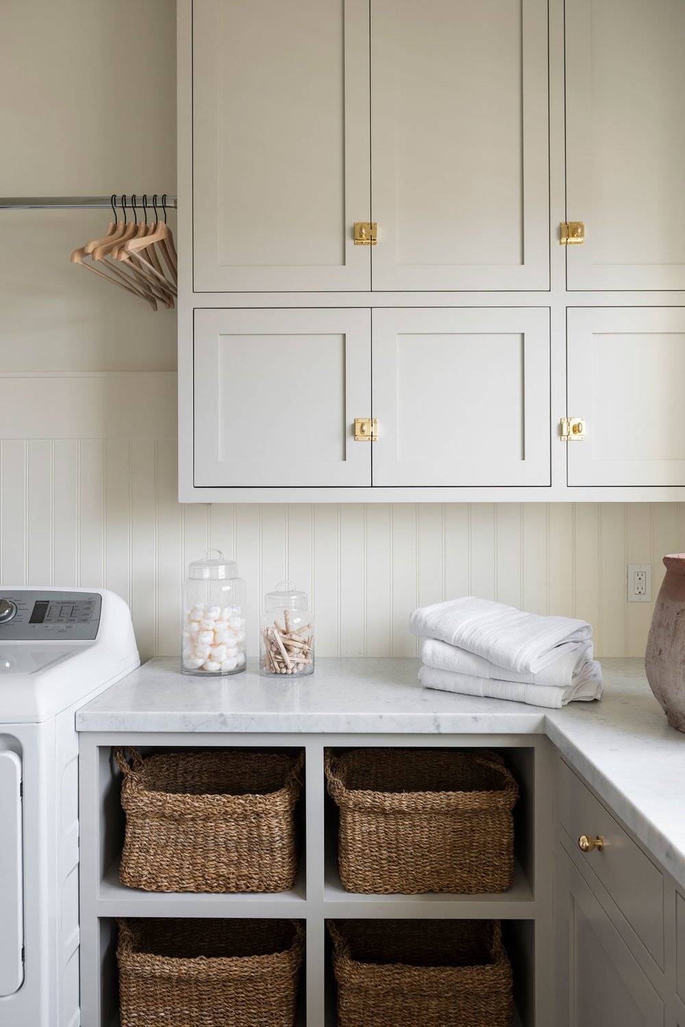 A laundry room with cabinets painted in Revere Pewter from Benjamin Moore, designed by Studio McGee