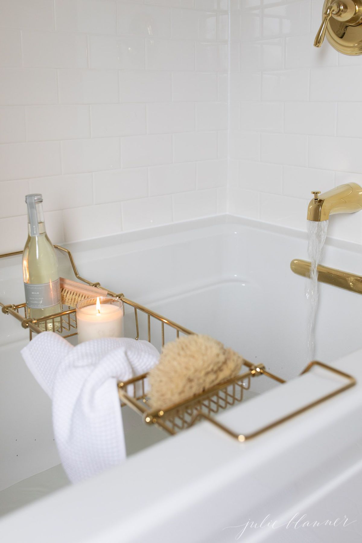 A spa bath with a gold bathtub tray filled with bath stuff