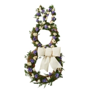 This spring wreath features purple flowers and a bow, perfect for adding a touch of charm to your decor.