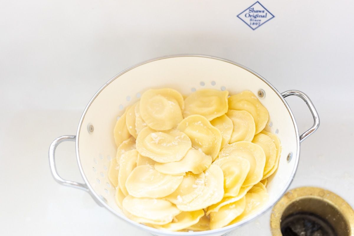 ravioli pasta in a white colander, draining