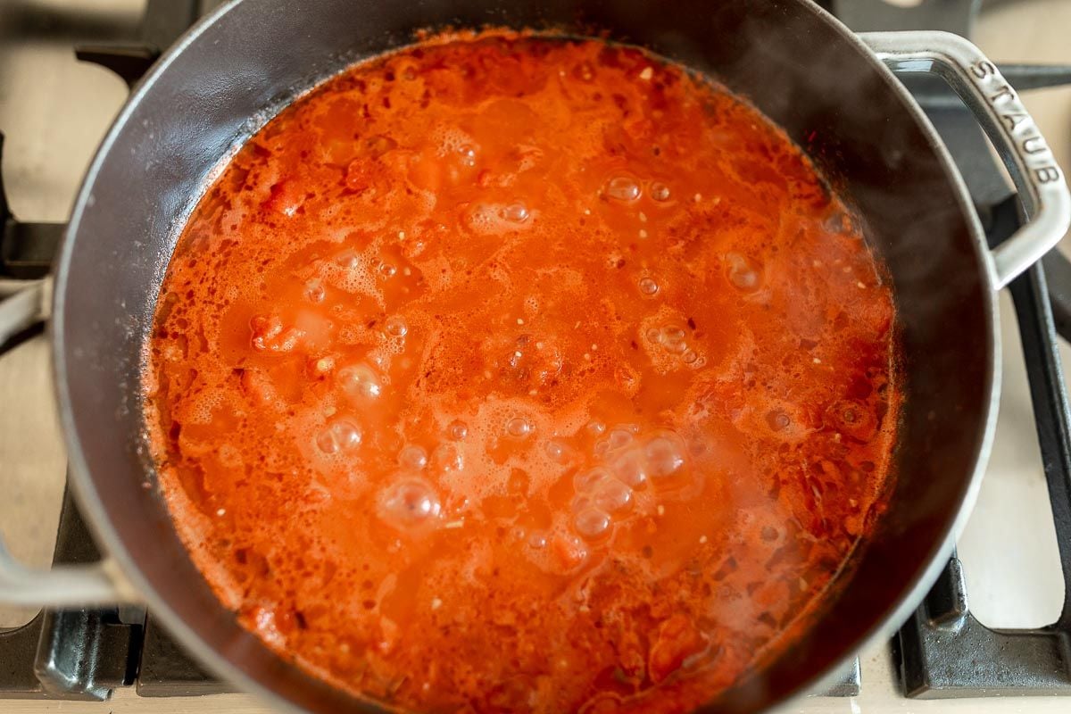 A red sauce simmering in a cast iron pan