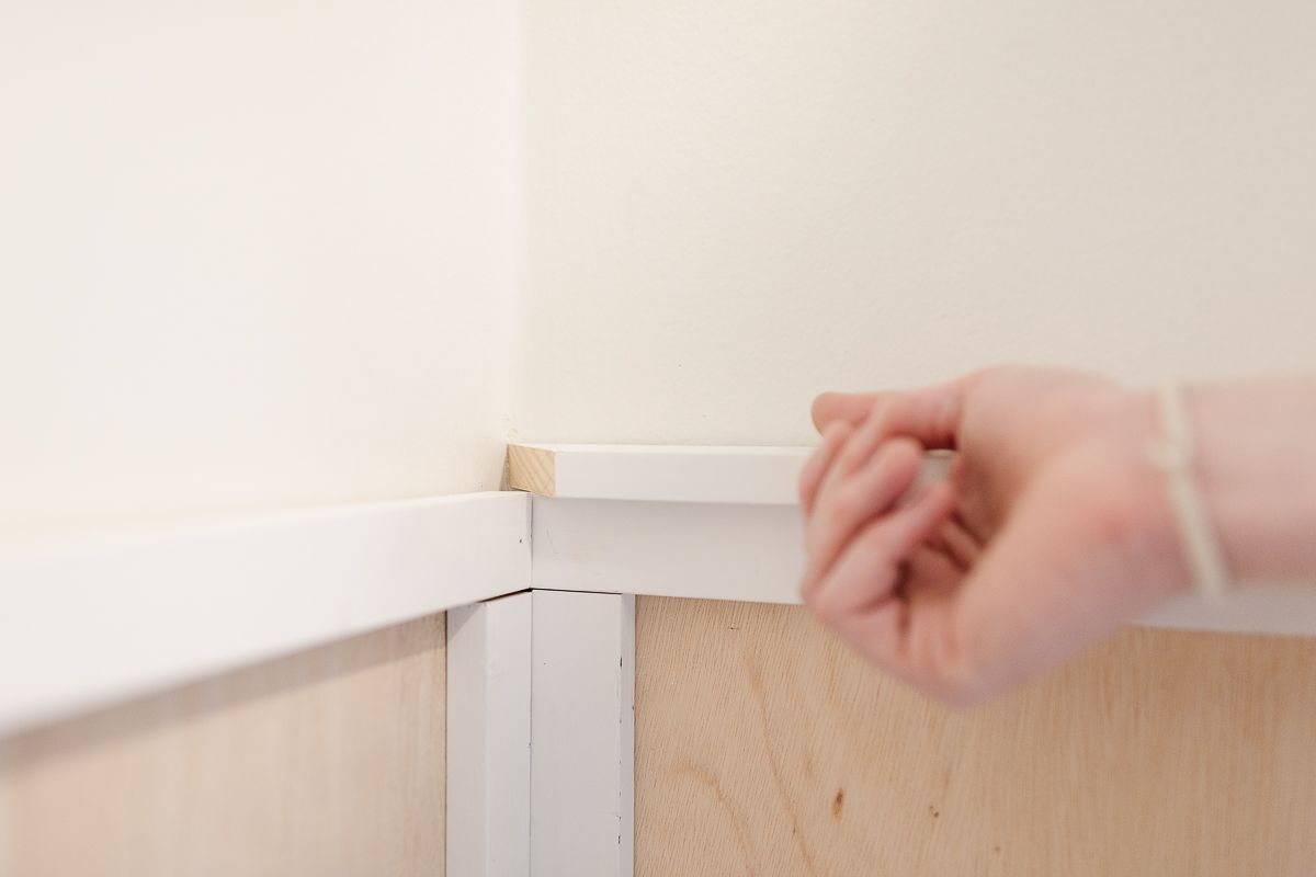 Hands holding trim on top of board and batten