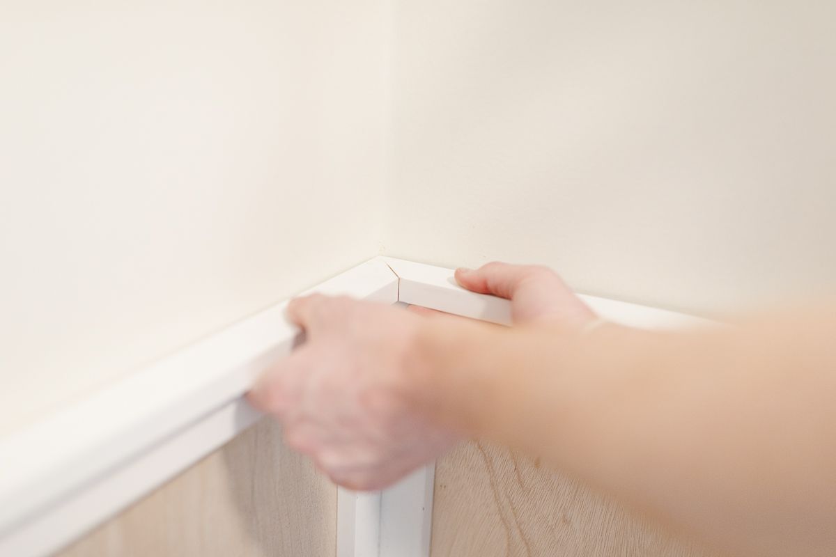 Hands holding trim on top of board and batten