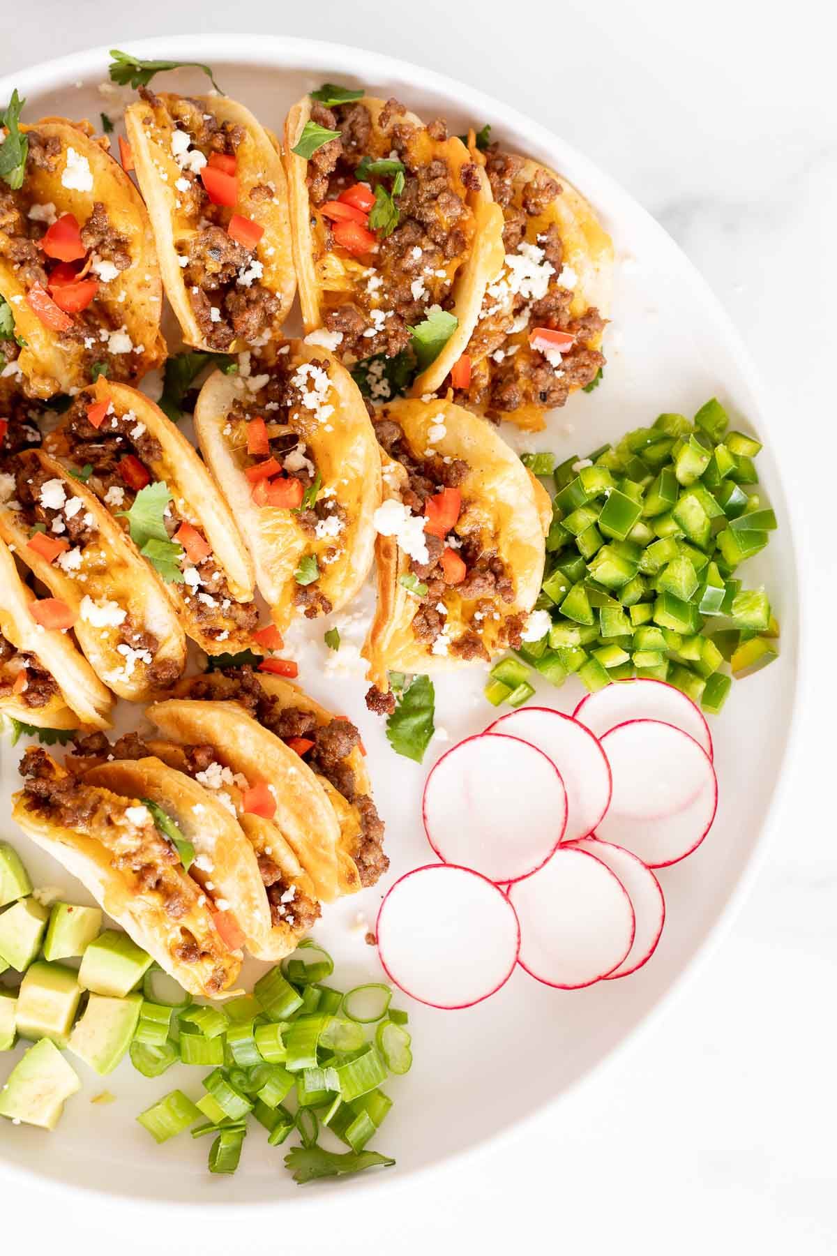 A white platter full of mini tacos