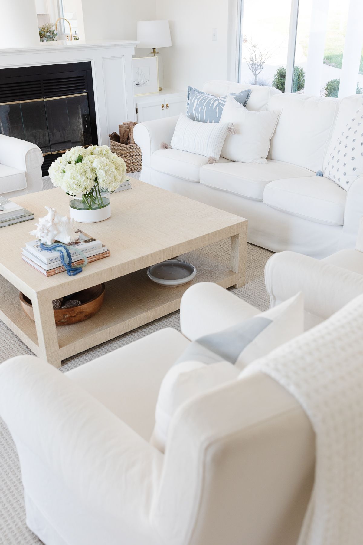 A living room with white furniture and a raffia coffee table