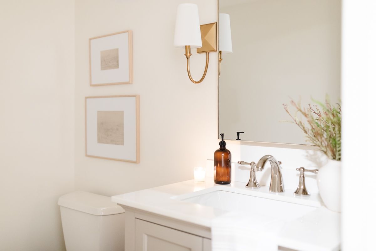 A bathroom with cream walls and gold sconces