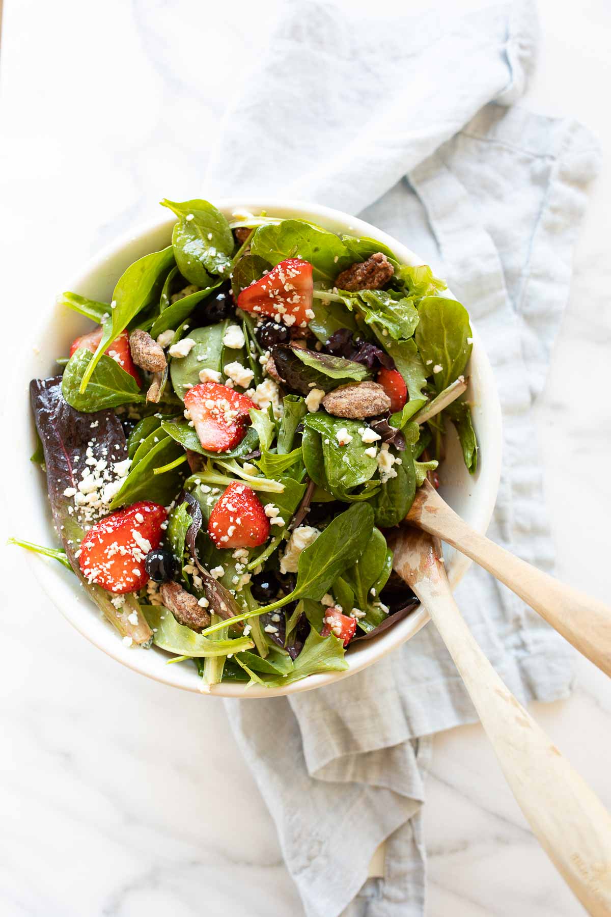 A bowl of spinach salad with strawberries and walnuts, perfect for Easter side dishes.