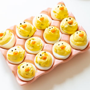 A tray of deviled eggs with yellow food faces, perfect for Easter side dishes.