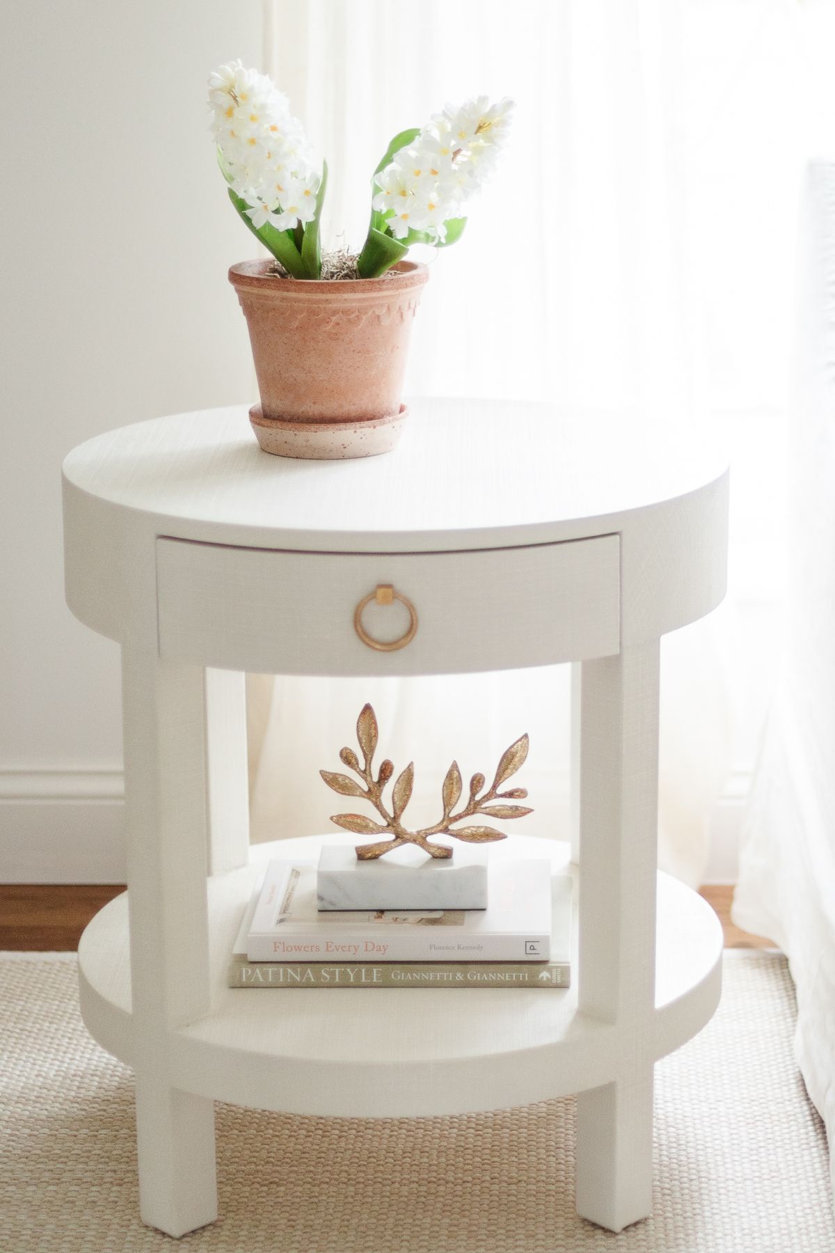 White faux flowers on a round white end table.