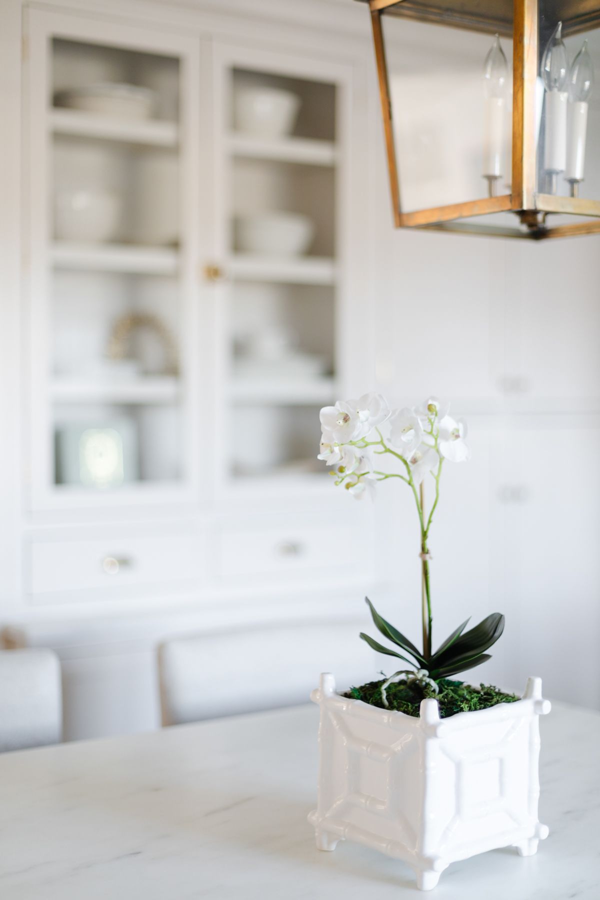 White orchid faux flowers in a cream kitchen.