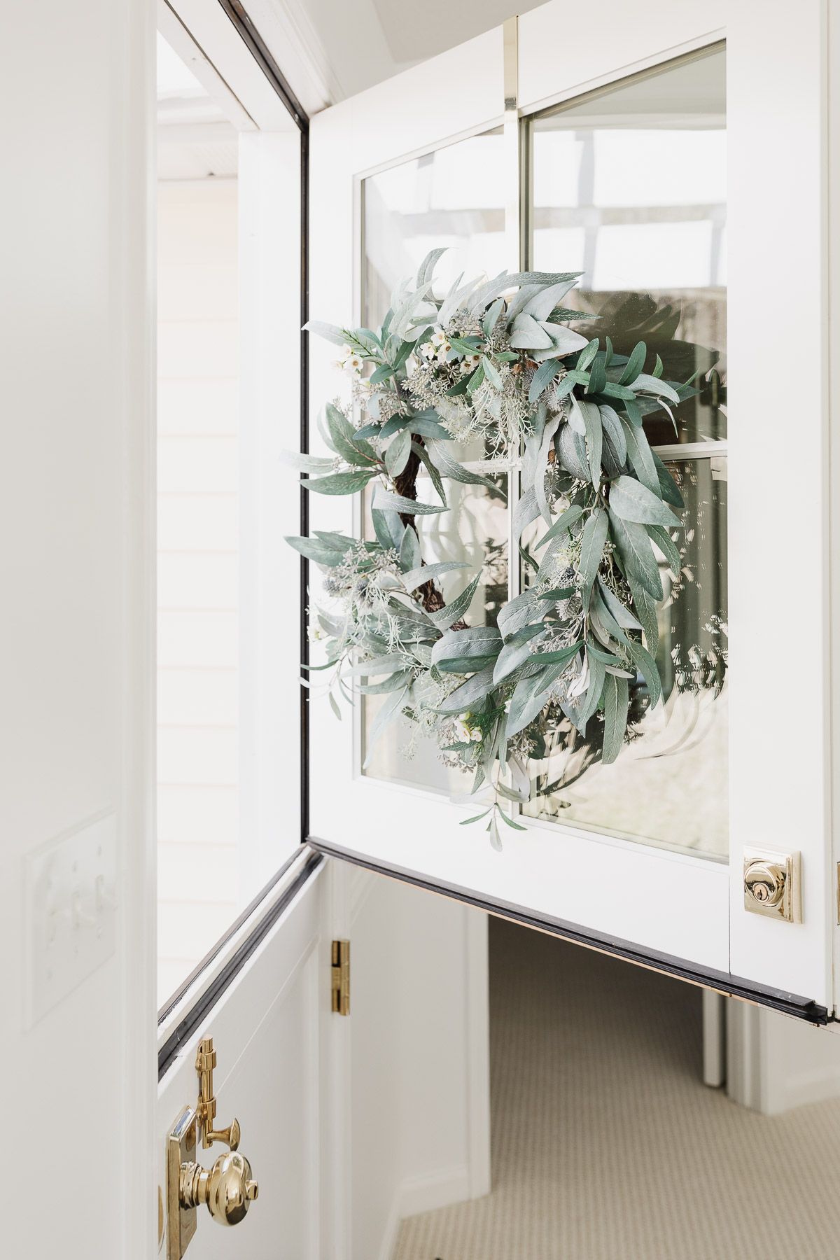A year round front door wreath in shades of grayish greens on a white dutch door.