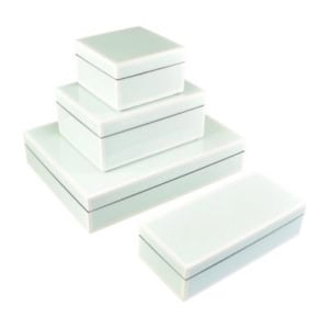 Four white rectangular boxes of varying sizes are stacked, with one placed separately in front—perfect inspiration for creative nightstand decorating.