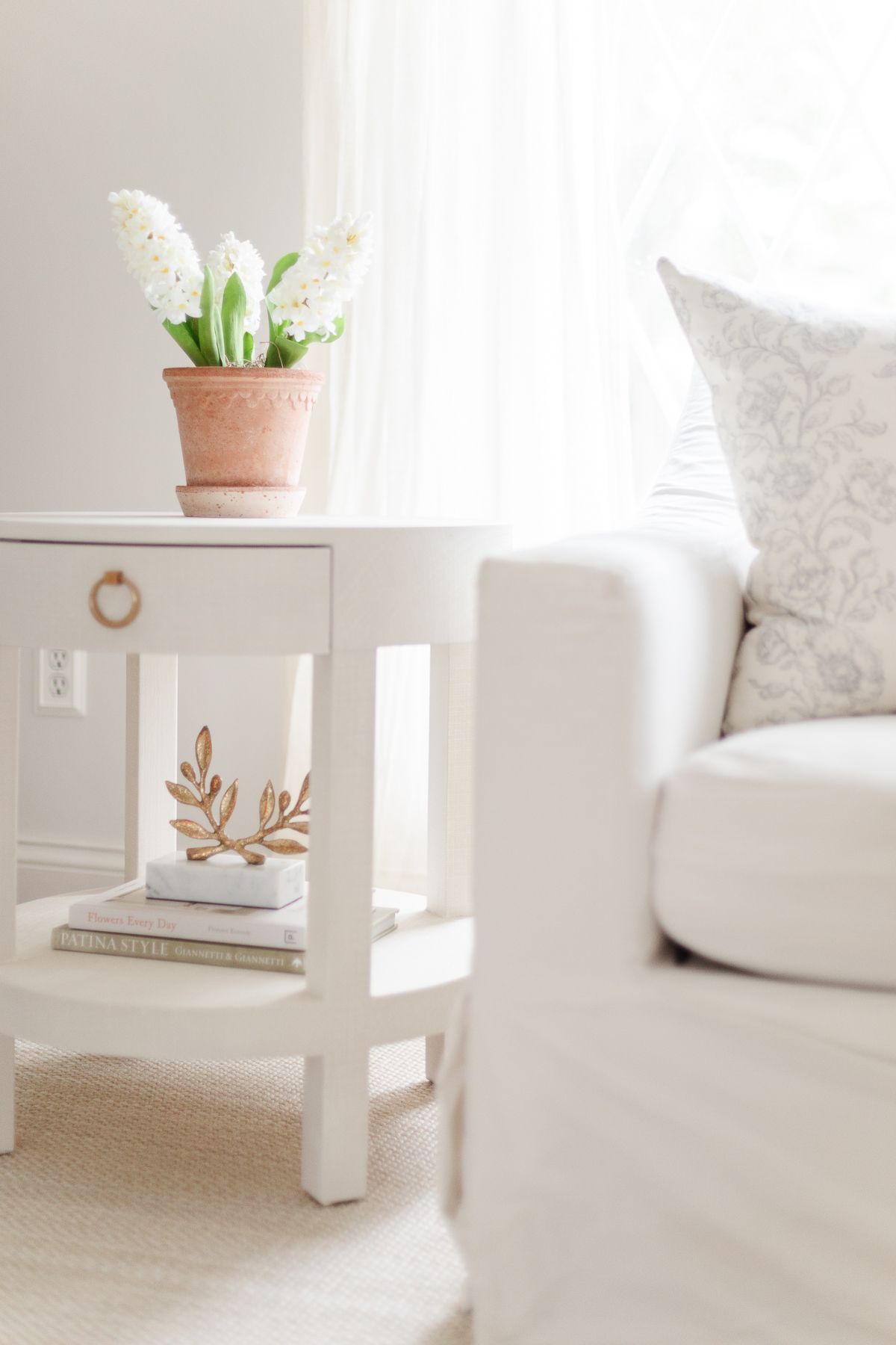 White faux flowers in a scalloped bergs pot.