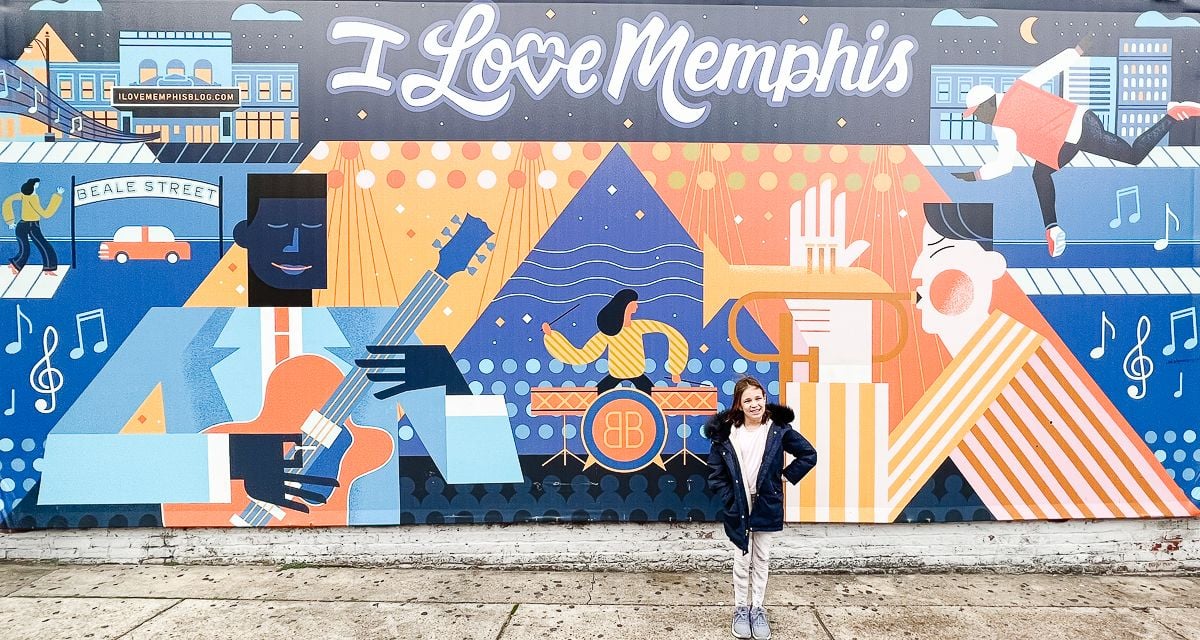 A little girl in front of a colorful "i love memphis" mural