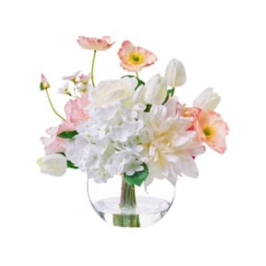 A clear glass vase holds a mixed bouquet of white hydrangeas, tulips, roses, and light pink poppies with green leaves—perfect for nightstand decorating.