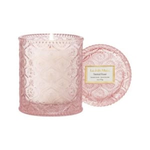 A pink, textured glass candle jar with a matching lid placed beside it. The lit candle inside adds a cozy touch, making it perfect for nightstand decorating. A label on the lid reads "La Jolie Muse Santal Rosé.