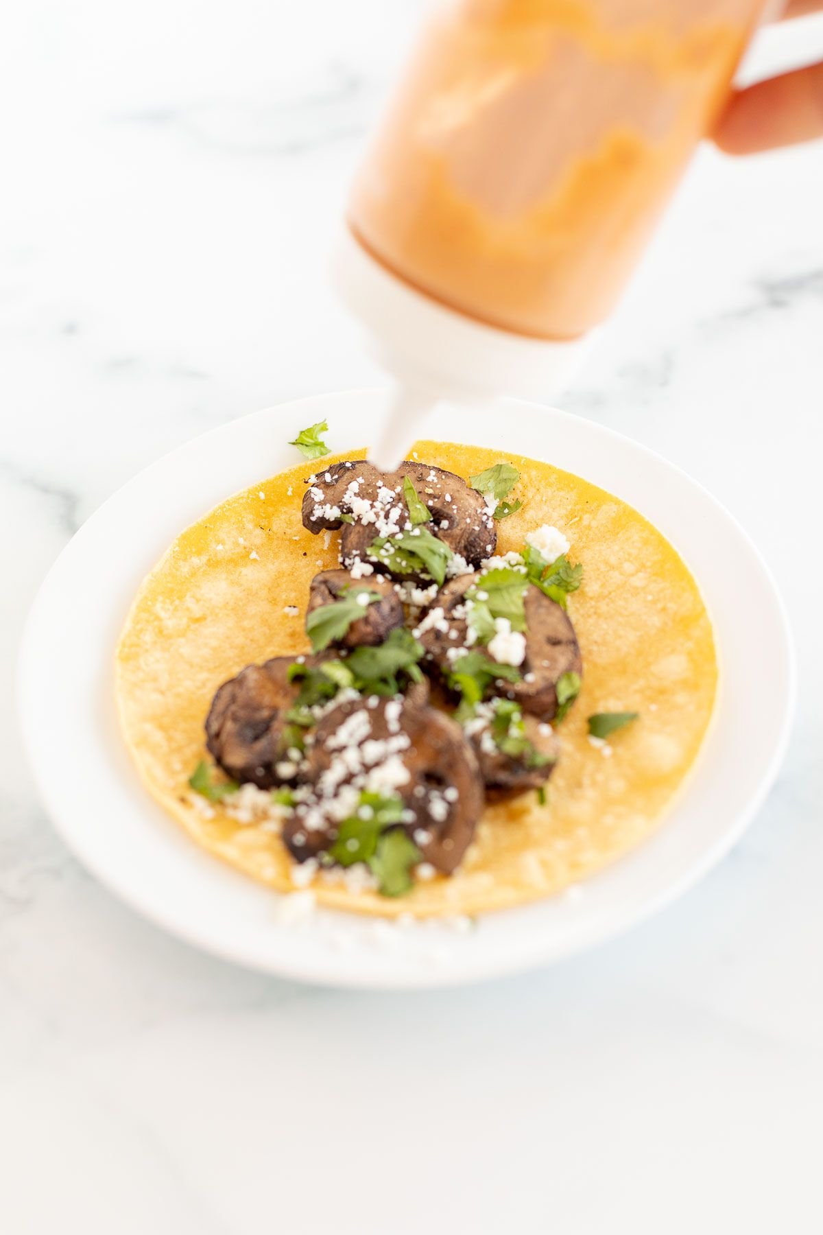 A portobello mushroom taco in a corn tortilla on a white plate