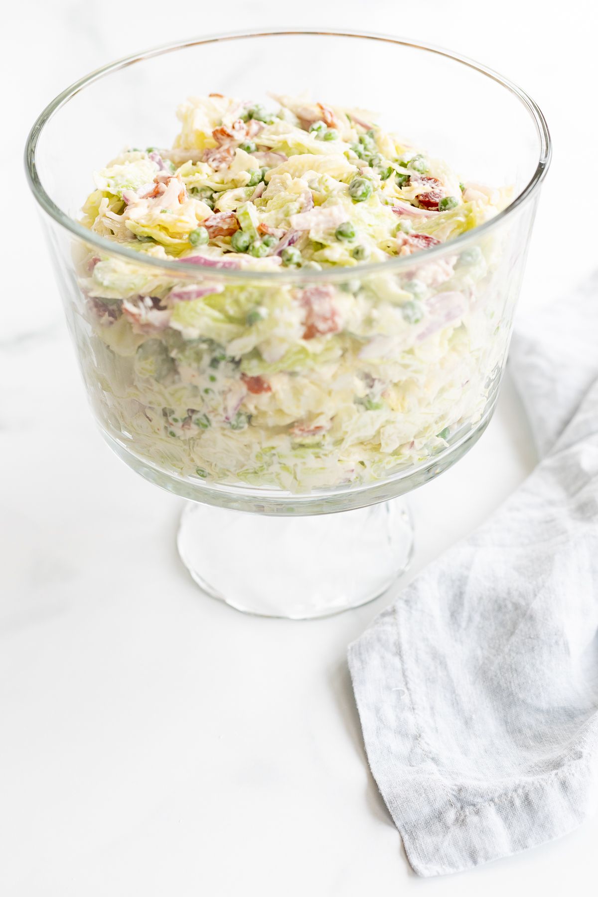 A 7 layer salad mixed up in a glass serving dish