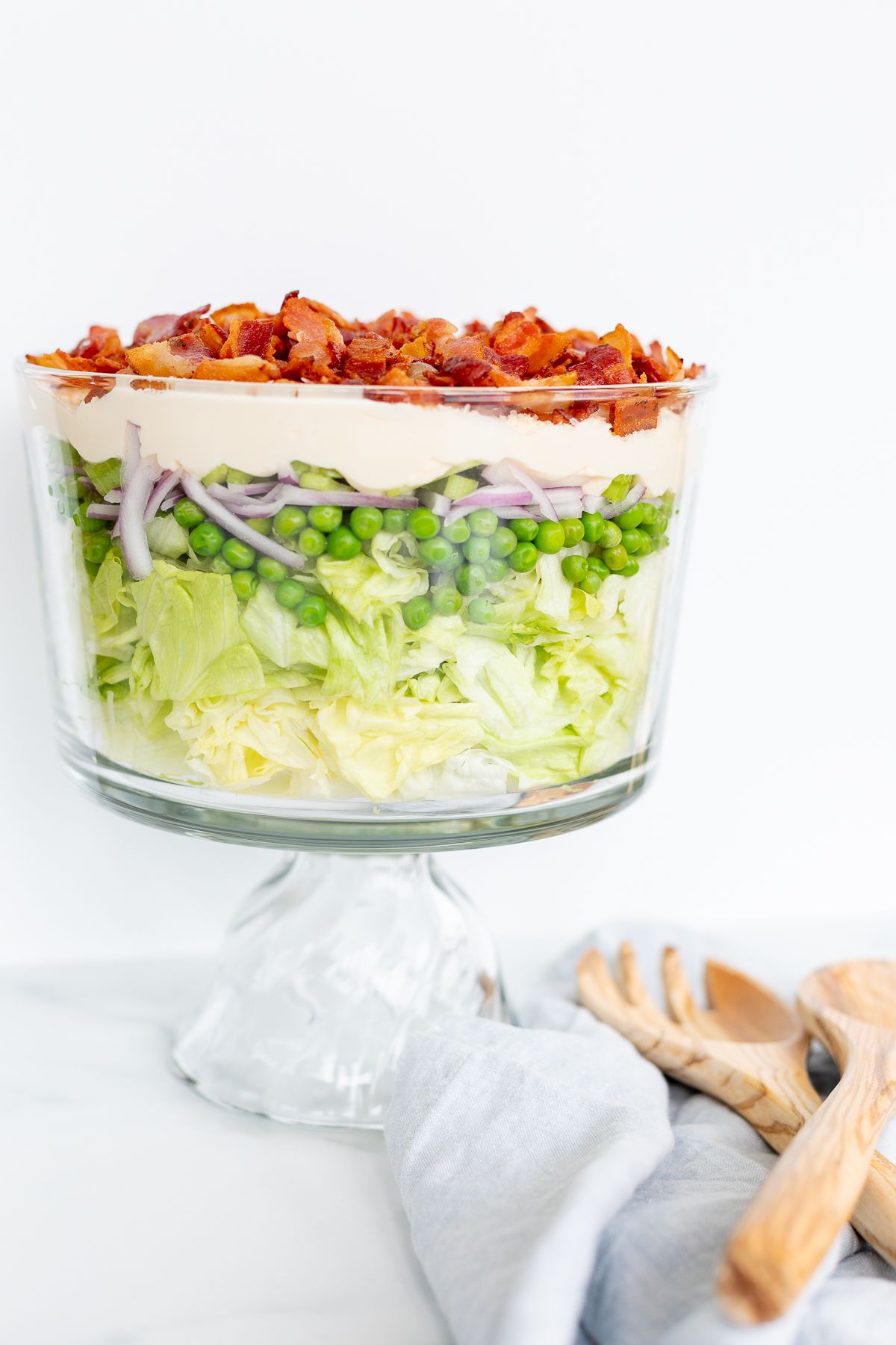 Seven layer salad topped with bacon on a marble countertop