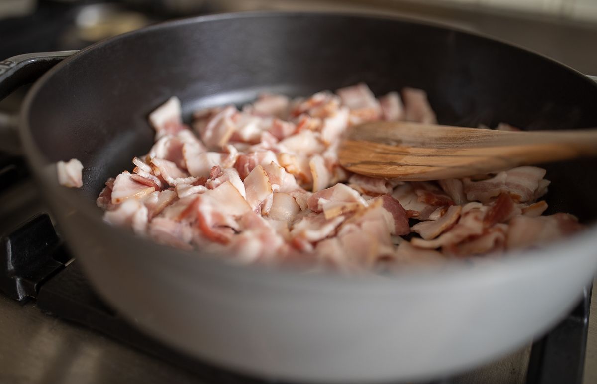 Chopped bacon cooking in a frying pan