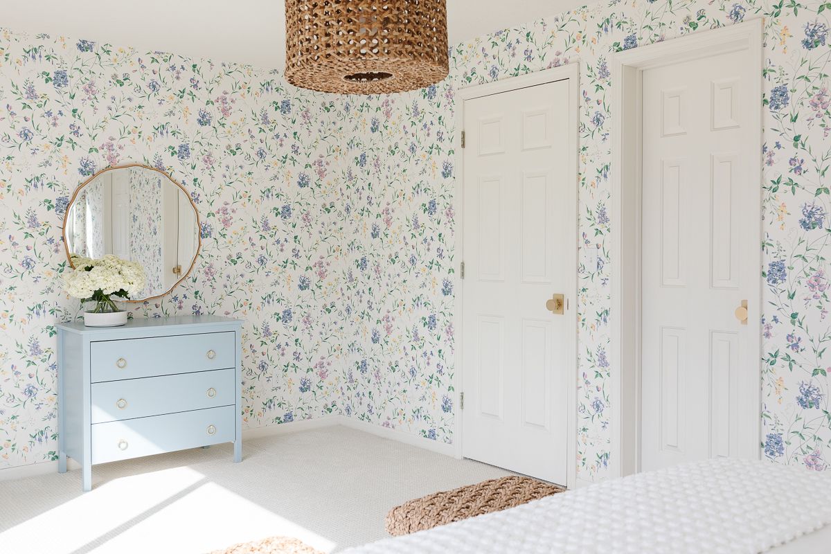 A bedroom with floral wallpaper and painted vanity in blue by Benjamin Moore Slate