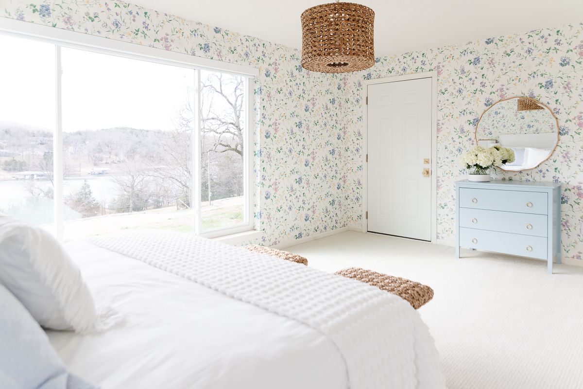 A bedroom with floral wallpaper and painted vanity in blue by Benjamin Moore Slate