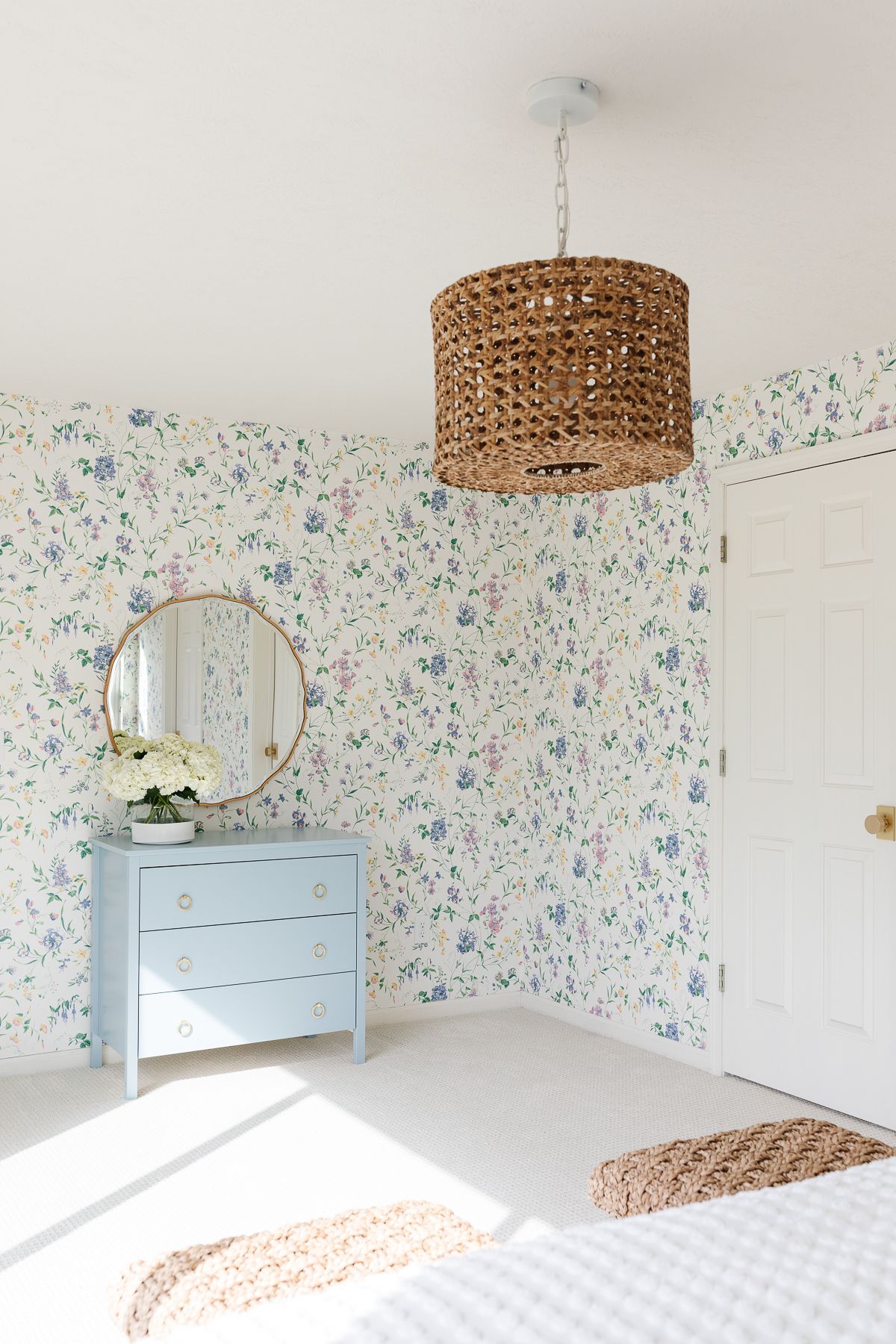 A bedroom with floral wallpaper and painted vanity in blue by Benjamin Moore Slate