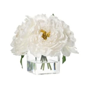 A clear glass vase holds three large white peony flowers with yellow centers and green stems, arranged in clear water—an elegant touch for nightstand decorating.