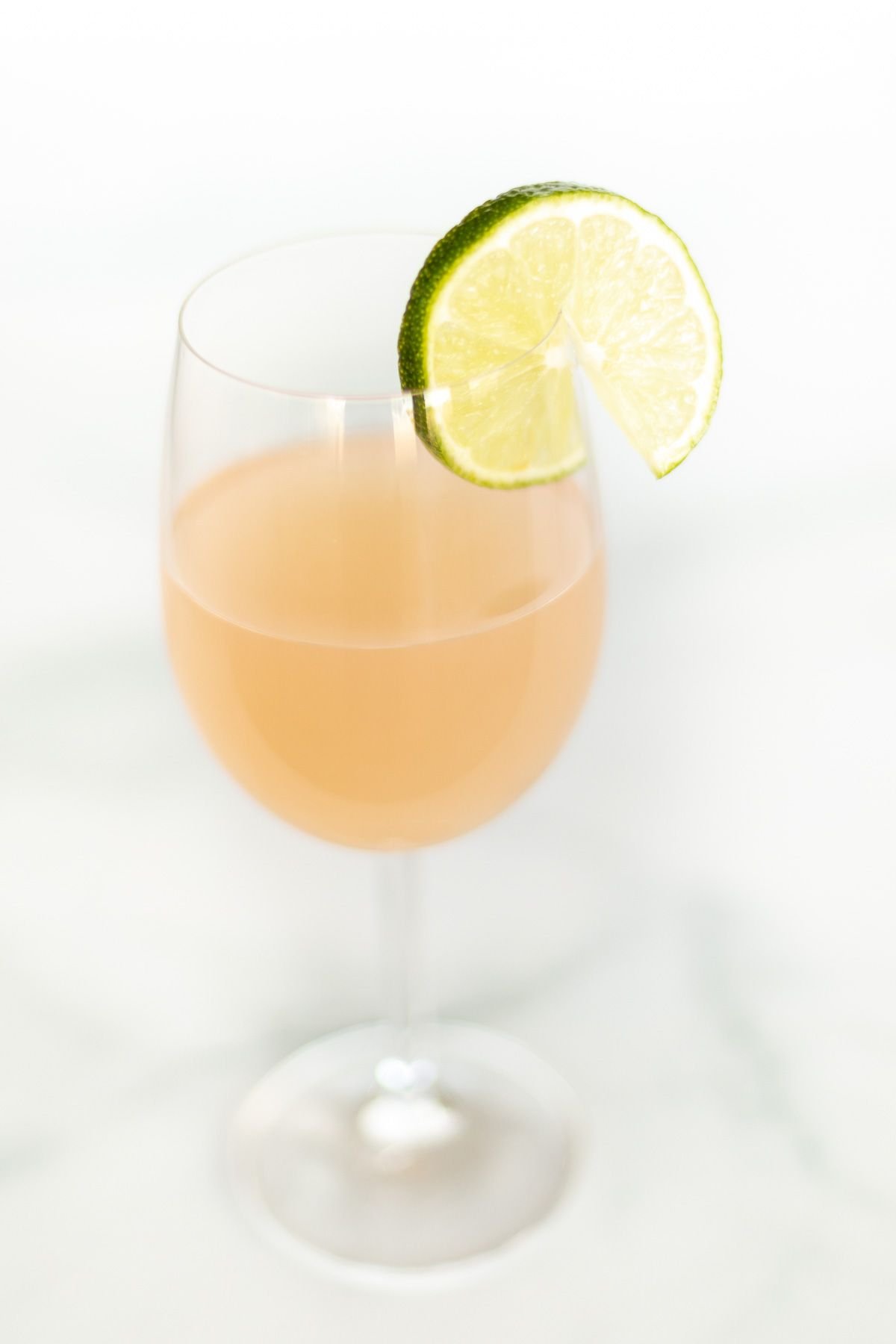 A wine margarita cocktail in a wine glass, garnished with a slice of lime
