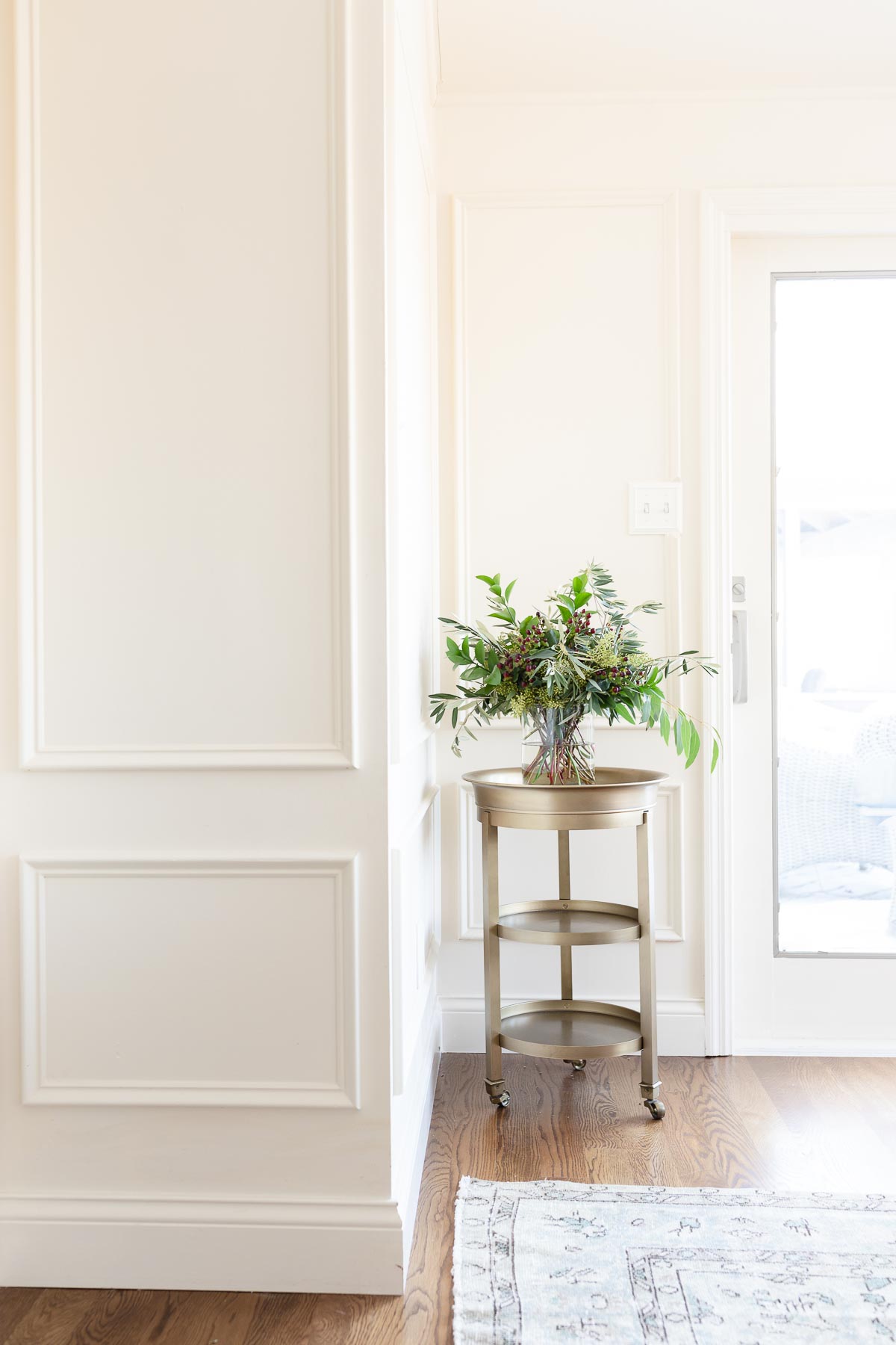 A dining room with a cream paint color on the walls and wood floors.