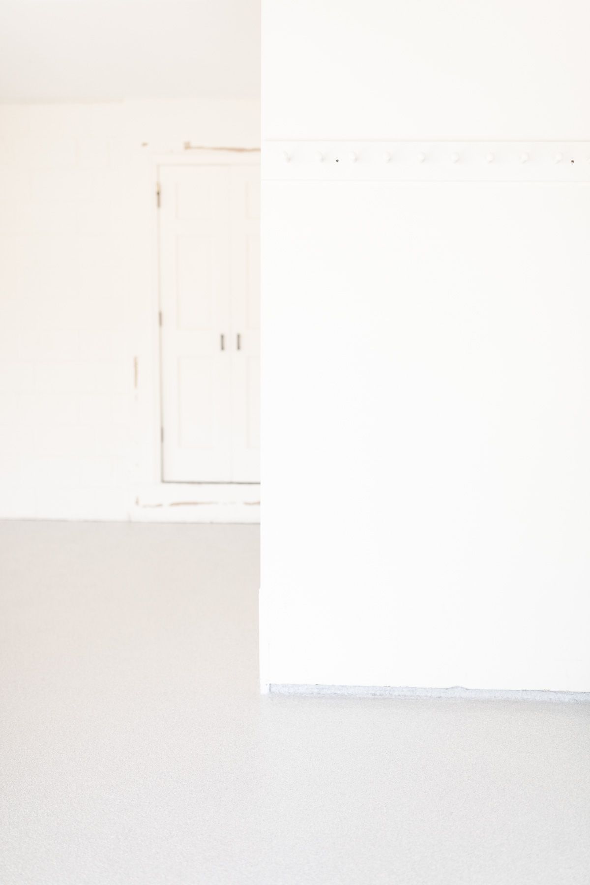 White garage with gray polygonal floor covering.