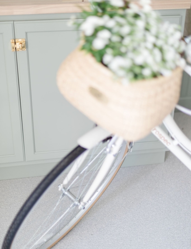 A white bike with a flower basket, in a garage with a greige garage floor coating.