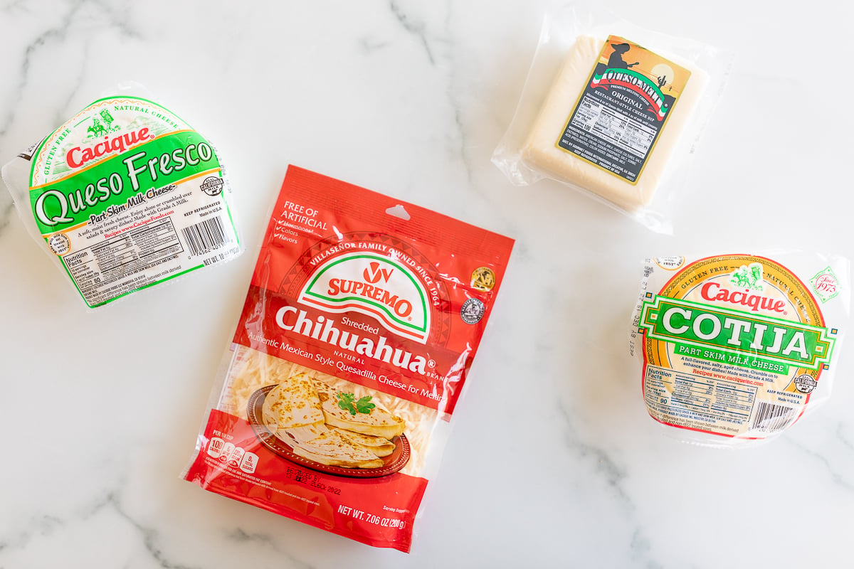 Four different types of Mexican cheese on a marble countertop.