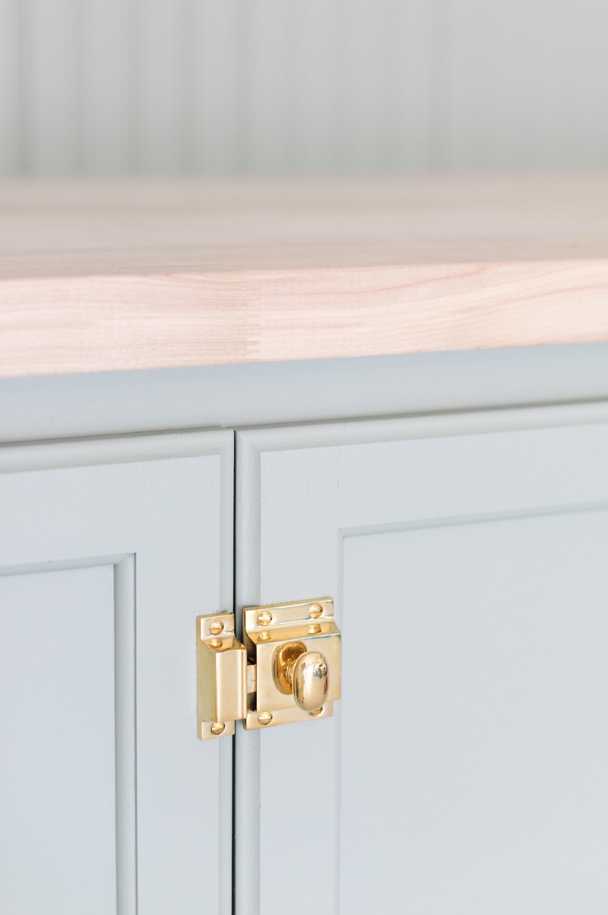 A green bench with brass hardware and cabinet latch