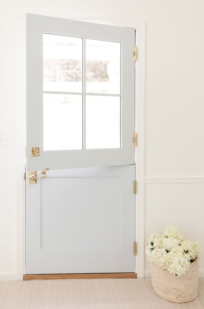A dutch door painted in a coastal blue paint color, basket of flowers on the floor
