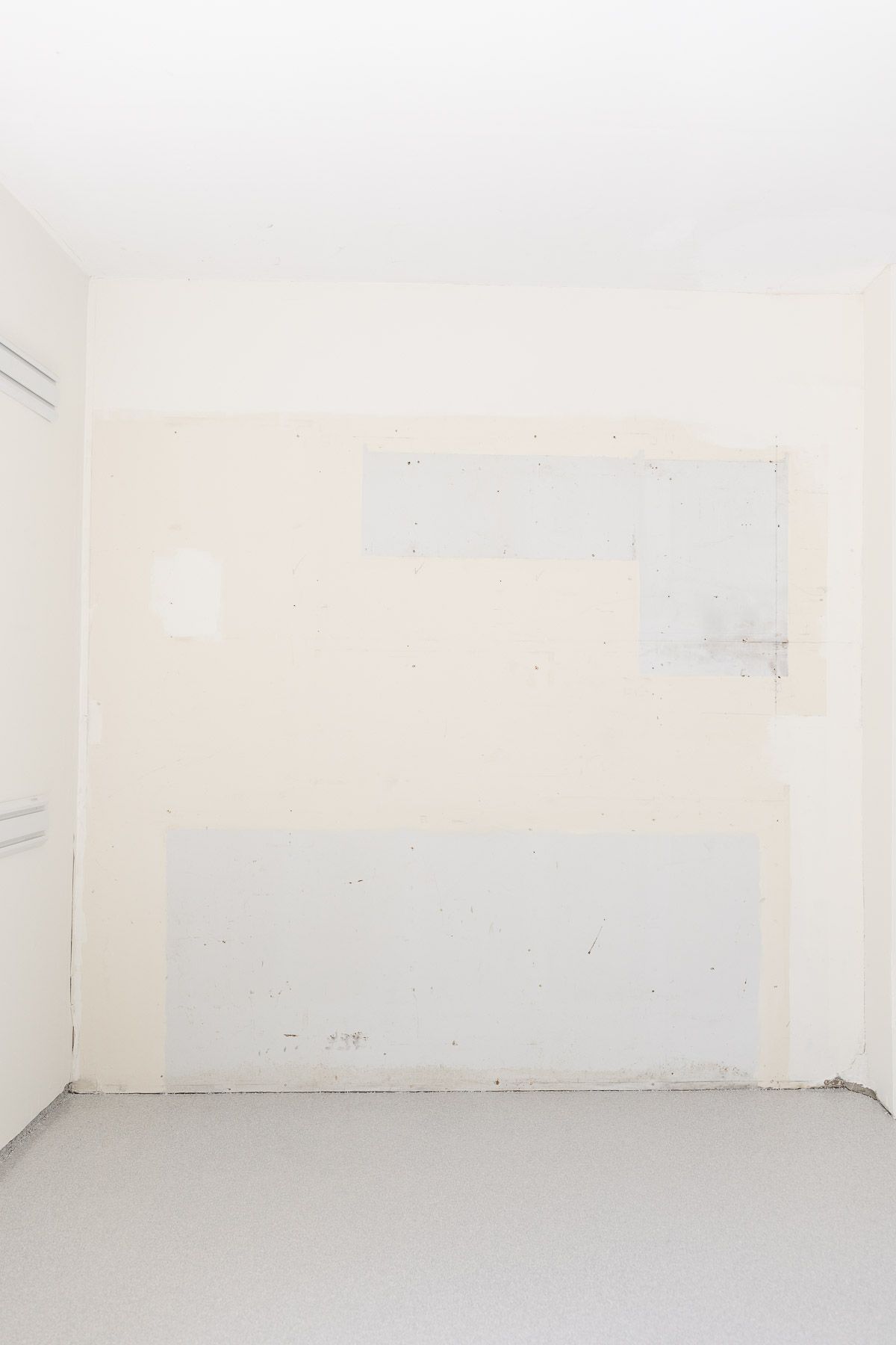 An empty space in a garage with mismatched wall paint