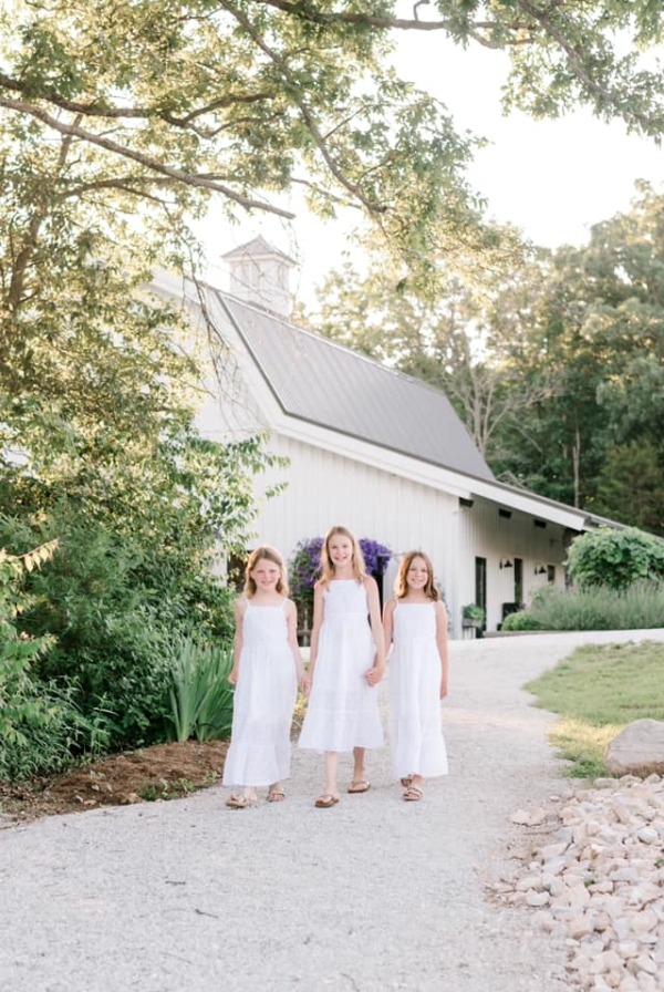 three little girls in white dresses in front of a white church