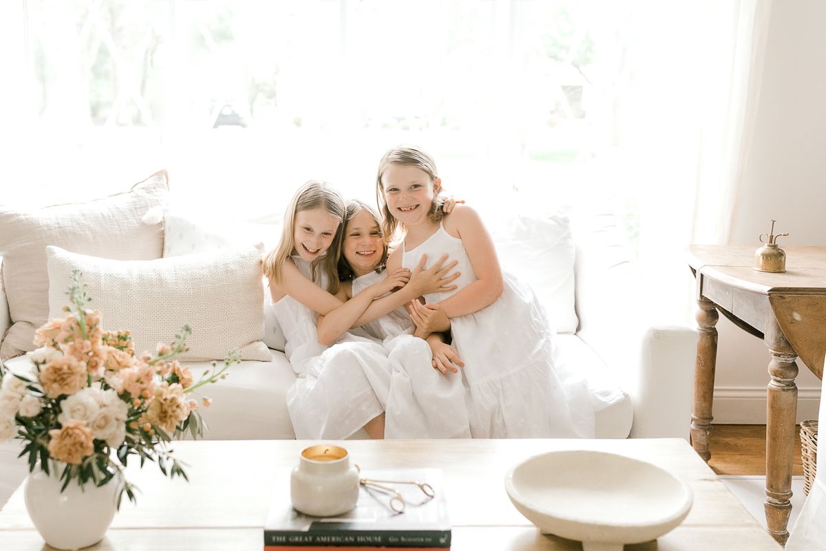 three little girls in white dresses on a white sofa