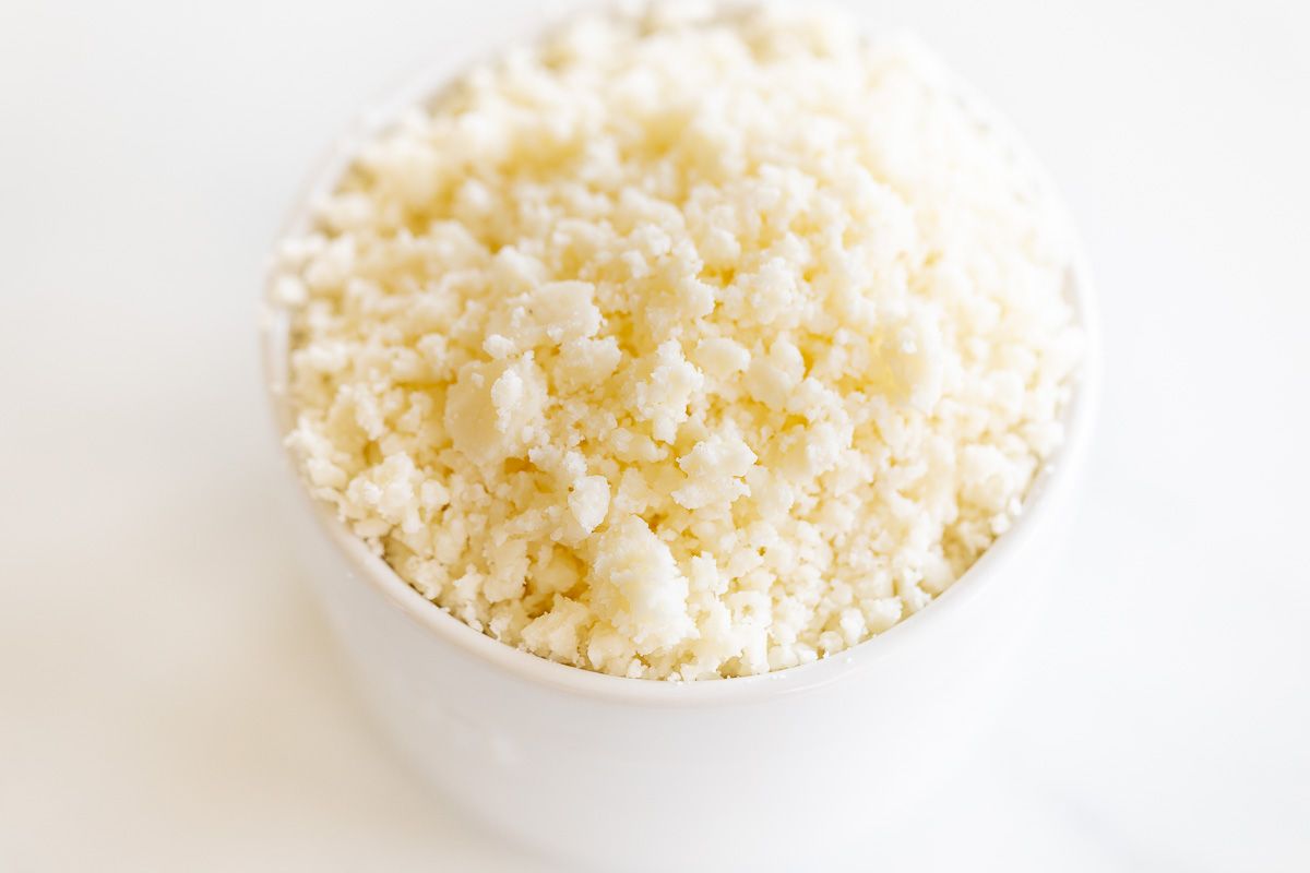 A white bowl full of crumbled white mexican cheese
