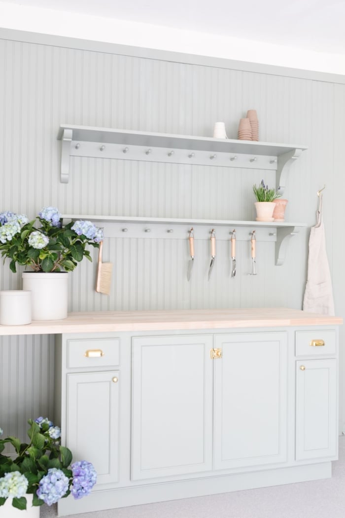Two hanging peg rails above a potting bench, painted green