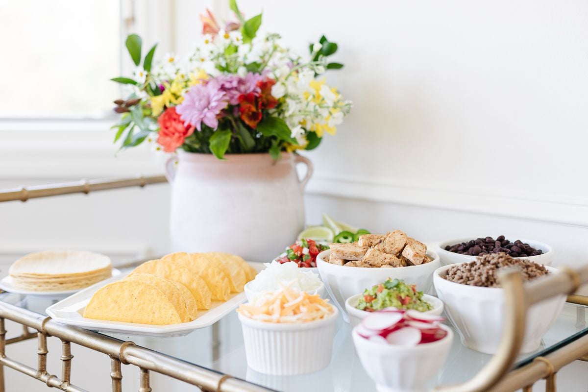 A taco bar display with flowers on a gold bar cart