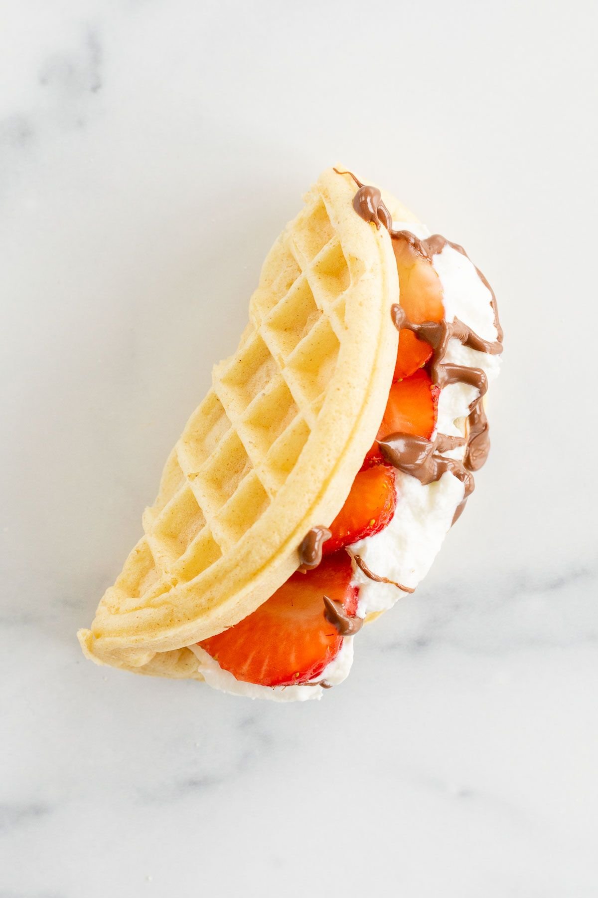 A waffle taco filled with strawberries, Nutella and whipped cream.