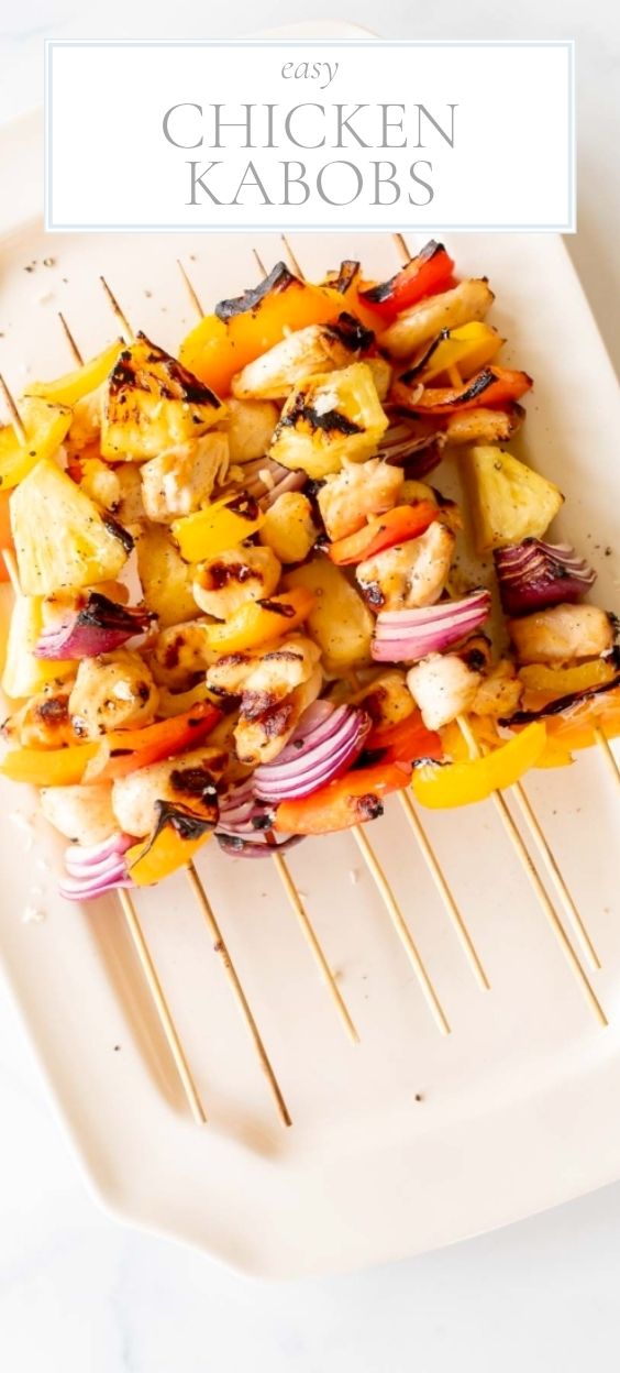 On a marble counter, there is a white platter of chicken kabobs.