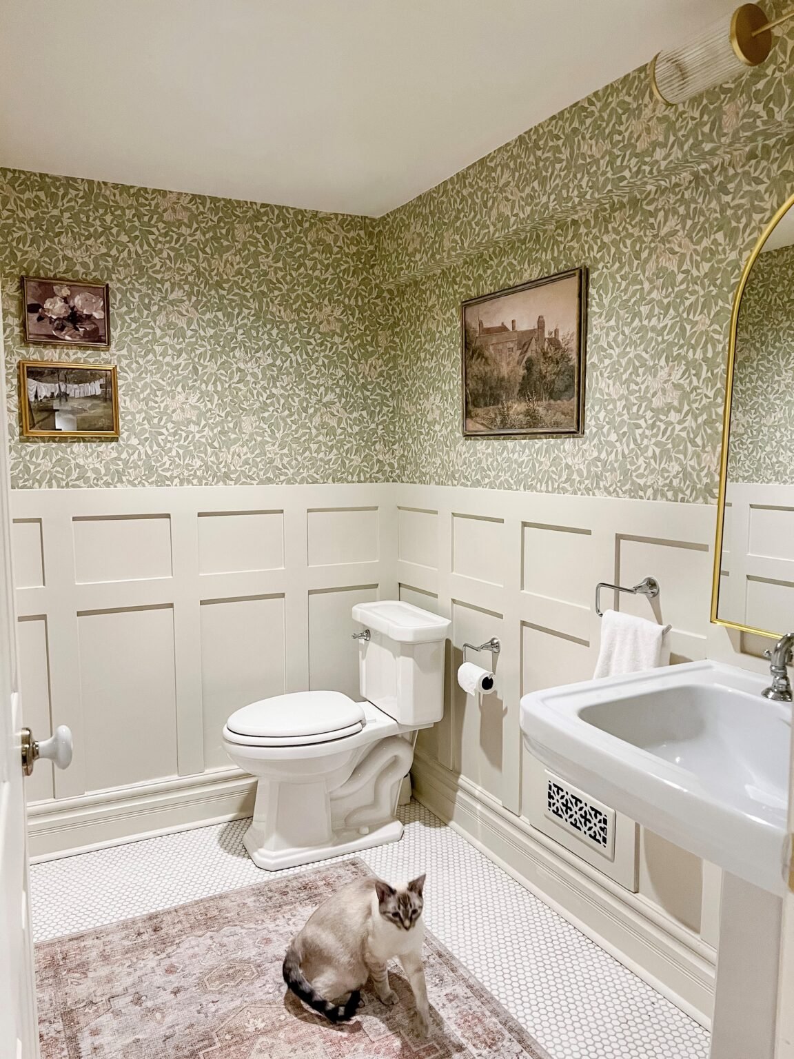 A wallpapered bathroom with board and batten on the bottom of the walls, painted in Natural Cream Benjamin Moore.