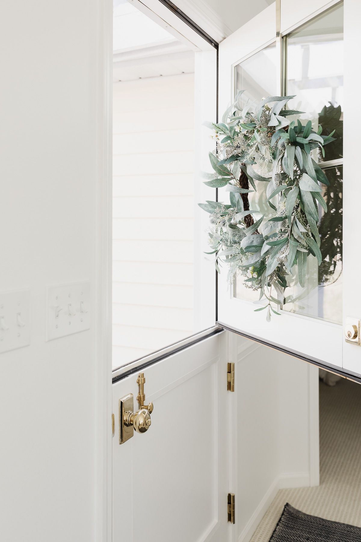 An open dutch door with brass hardware and a wreath on the top