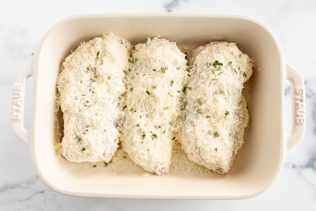 Mayo Parmesan chicken breasts before baking, placed in a white dish.