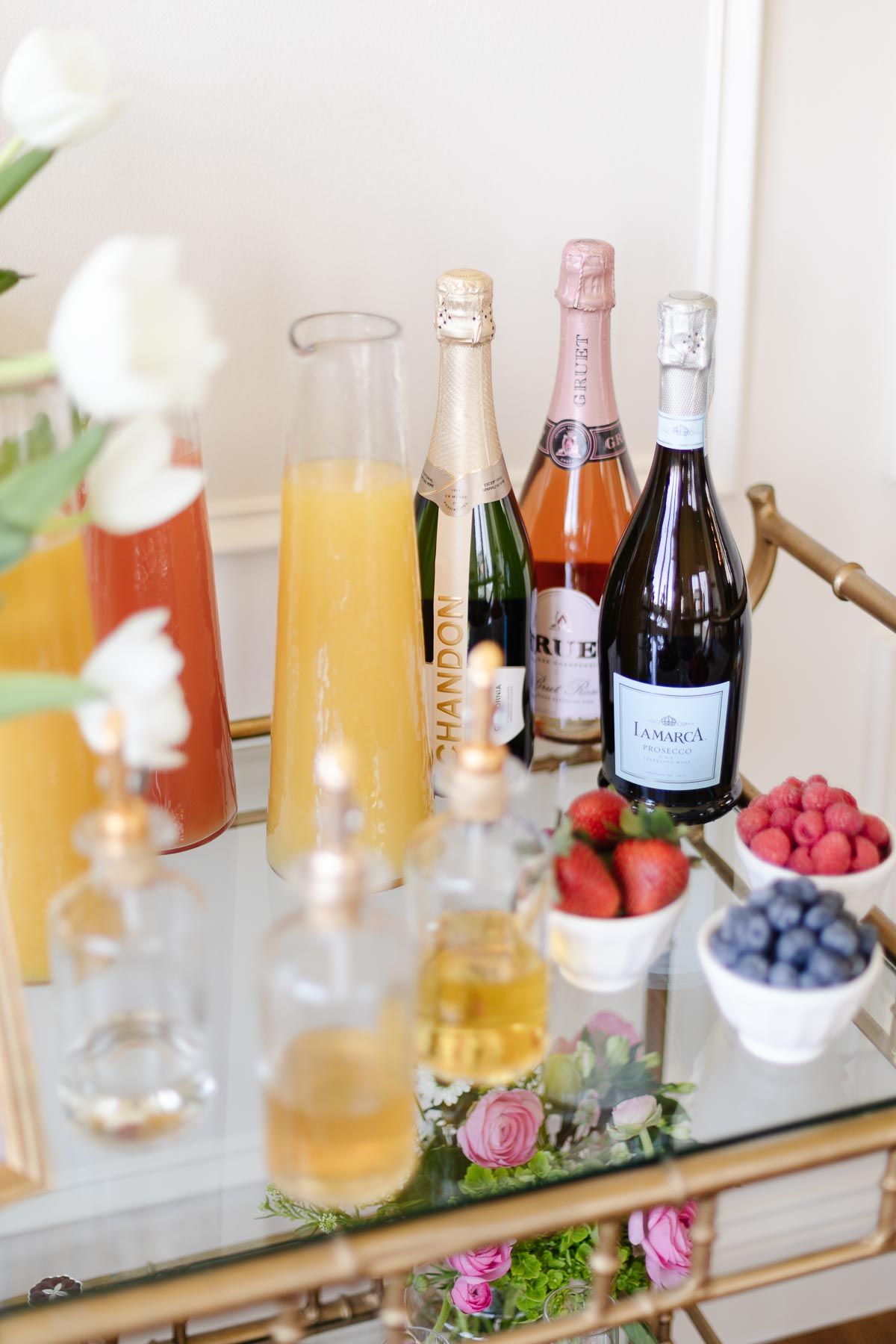 Champagne and fresh fruits and juices on a gold bar cart