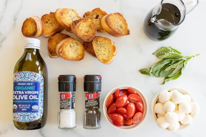 Mozzarella bruschetta ingredients laid out on a marble surface