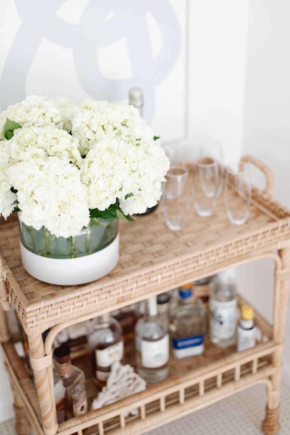 A rattan bar cart with a vase of white hydrangea